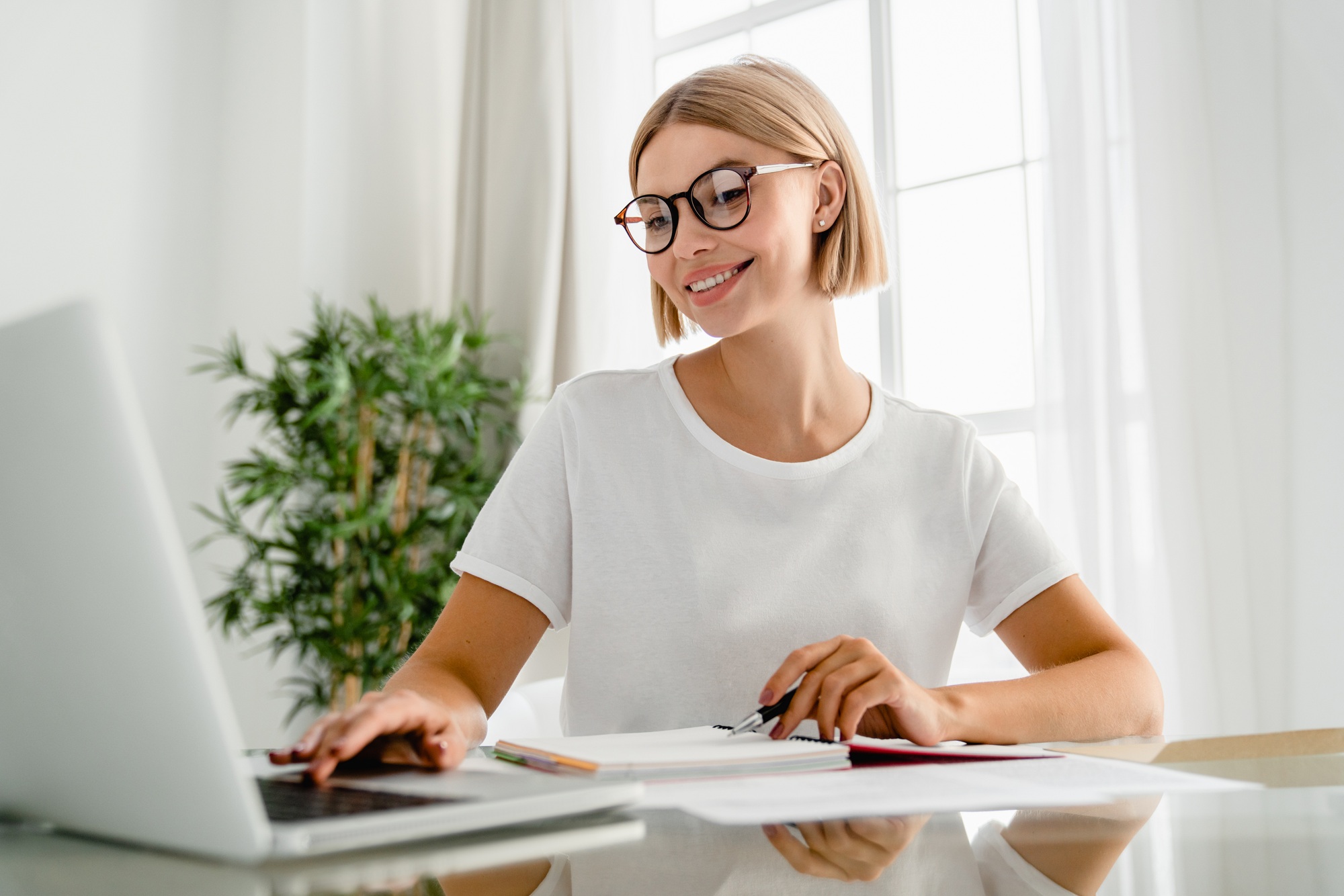 Young caucasian female freelancer using laptop for e-learning at home desk.